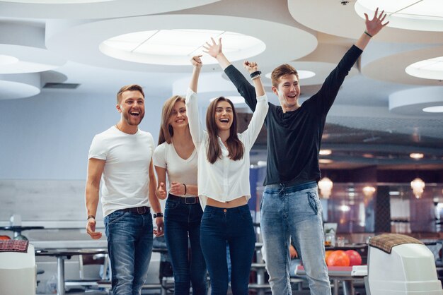 Gracias por el fantástico juego. Jóvenes amigos alegres se divierten en el club de bolos en sus fines de semana