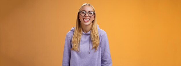 Graciosa y encantadora programadora divirtiéndose mostrando la lengua engañando a sus compañeros de trabajo durante el almuerzo smi