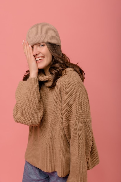 Graciosa joven morena caucásica con sombrero que cubre la mitad de la cara con la mano sobre fondo rosa Personas emociones estilo de vida y concepto de moda