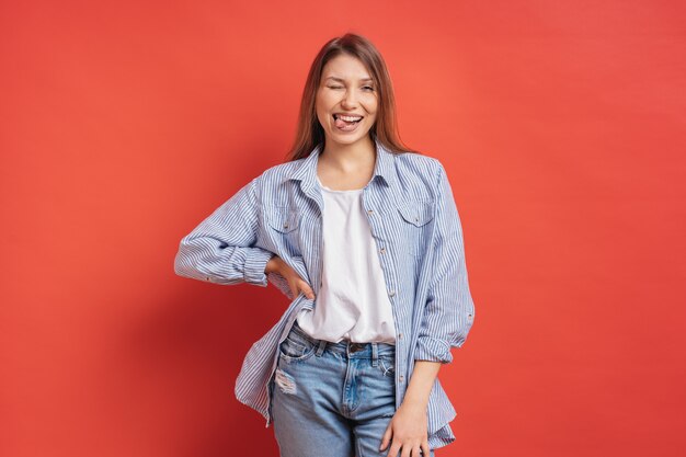 Graciosa, linda chica divirtiéndose aislado en una pared roja