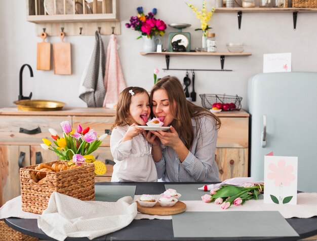 Graciosa madre e hija comiendo cupcake