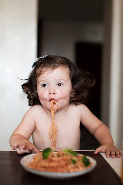 Graciosa niña comiendo espagueti