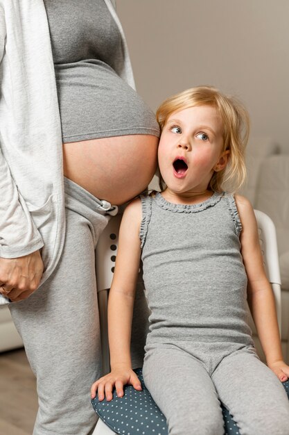 Graciosa niña escucha madre embarazada vientre