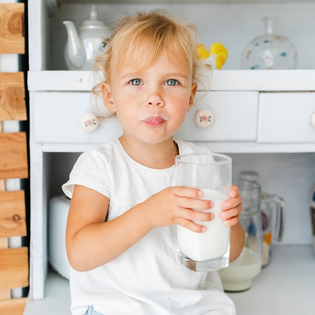 Foto gratuita graciosa niña sosteniendo un vaso de leche