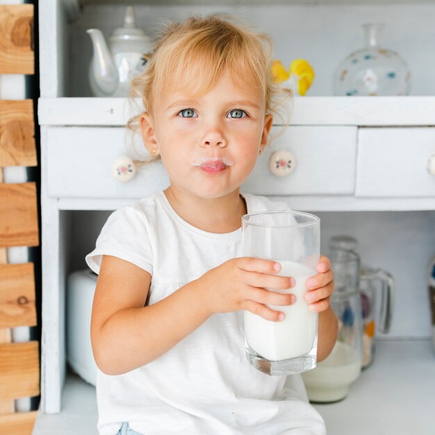 Graciosa niña sosteniendo un vaso de leche