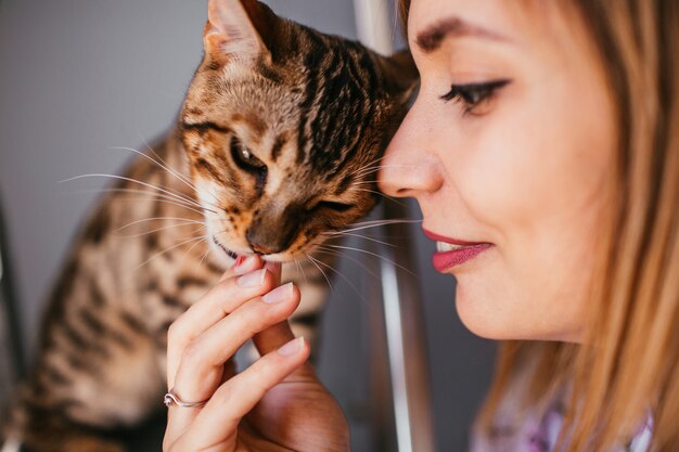 Gracioso gato de Bengala juega en la escalera de acero con una mujer