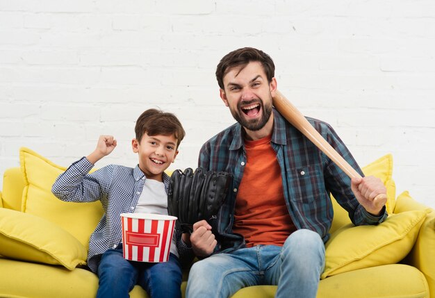 Gracioso hijo y padre sosteniendo un bate de béisbol