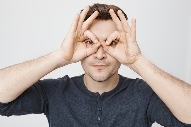 Gracioso joven haciendo gafas falsas con las manos