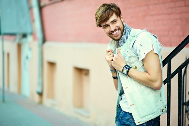 Gracioso sonriente hipster hombre guapo en elegante ropa de verano en la calle con gafas de sol