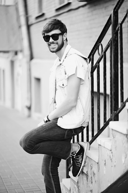 Gracioso sonriente hipster hombre guapo en elegante ropa de verano en la calle con gafas de sol