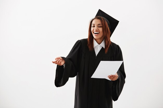 Graduado de soltero alegre feliz de la mujer africana que sonríe riendo durante el discurso de aceptación que lleva a cabo la prueba.