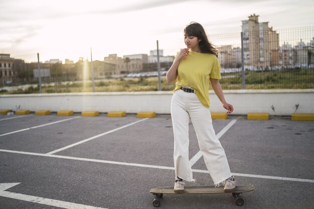 Gran angular de una niña en una patineta en un parque