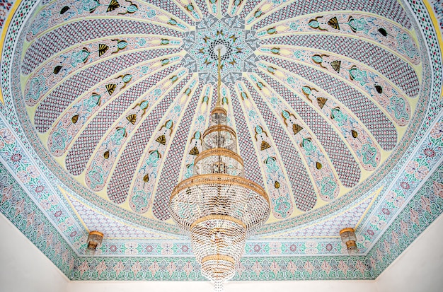 Gran candelabro dorado en un techo abigarrado con adornos religiosos tradicionales islámicos.