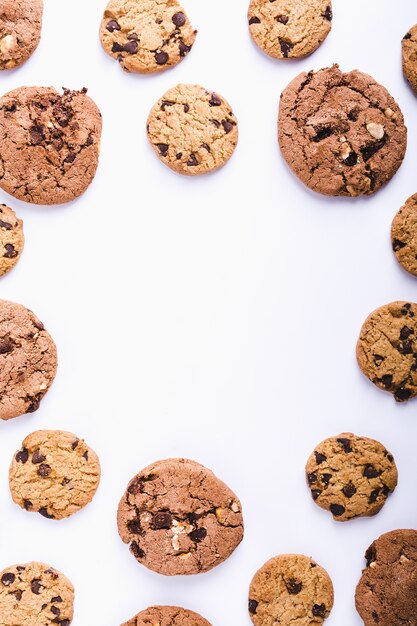 Gran cantidad de galletas con chispas de chocolate dispuestas en círculo sobre un fondo blanco con espacio de copia