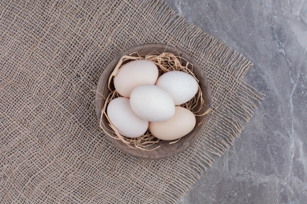 Una gran cantidad de huevos blancos de pollo frescos en un tazón de madera. Foto de alta calidad