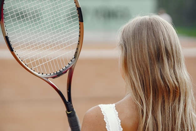 ¡Gran día para jugar! Mujer joven alegre en camiseta. Mujer sosteniendo pelota y raqueta de tenis.