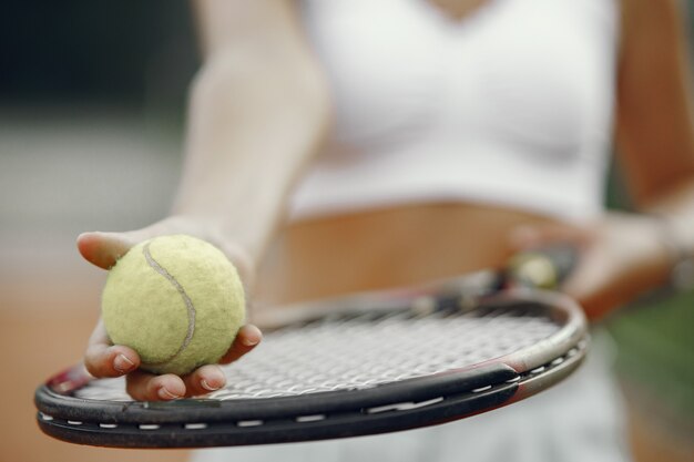 ¡Gran día para jugar! Mujer joven alegre en camiseta. Mujer sosteniendo pelota y raqueta de tenis.