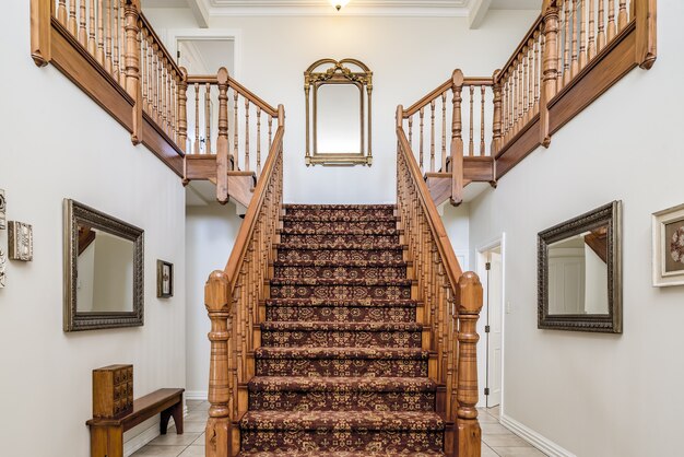 Gran escalera de madera con una alfombra vintage dentro de un apartamento con paredes blancas