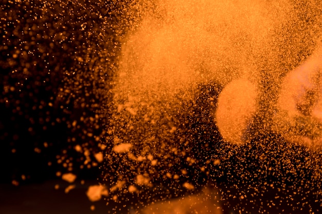 Gran explosión de polvo de maquillaje naranja sobre fondo oscuro