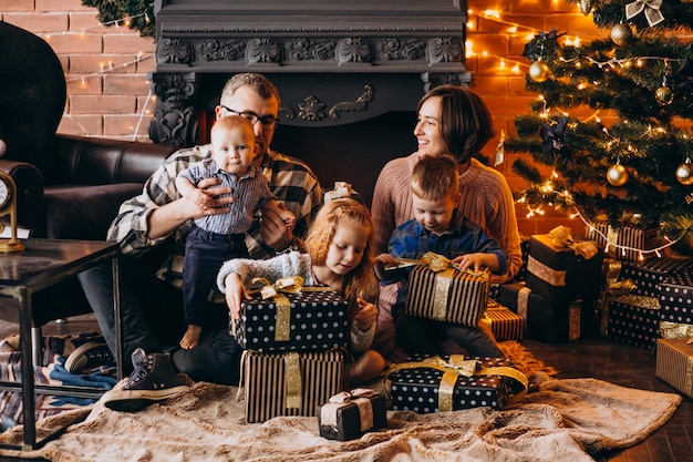 Gran familia en Nochebuena con regalos por árbol de Navidad
