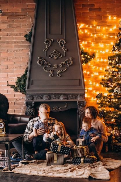 Gran familia en Nochebuena con regalos por árbol de Navidad