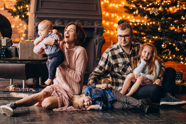 Gran familia en Nochebuena con regalos por árbol de Navidad