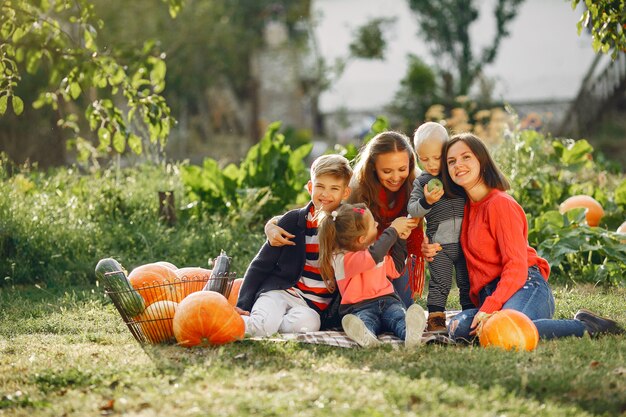 Gran familia sentada en un jardín cerca de muchas calabazas