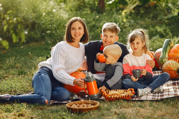 Gran familia sentada en un jardín cerca de muchas calabazas