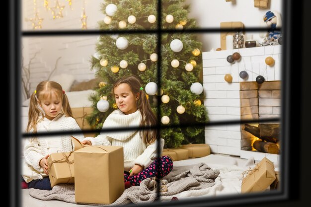 Gran familia con tres hijos celebrando la Navidad en casa. Cena festiva en chimenea y árbol de Navidad. Padres e hijos comiendo en la chimenea en una habitación decorada. Niño encendiendo velas de corona de adviento.