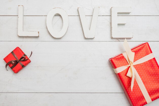 Gran inscripción de amor blanca cerca de cajas de regalo.