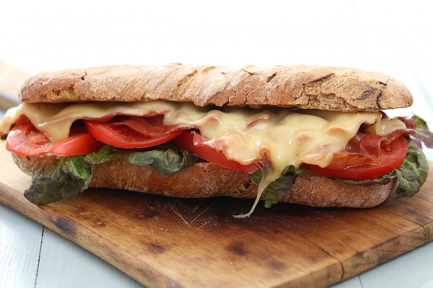 Gran sandwich vegano con verduras y queso en la mesa de tablero de madera