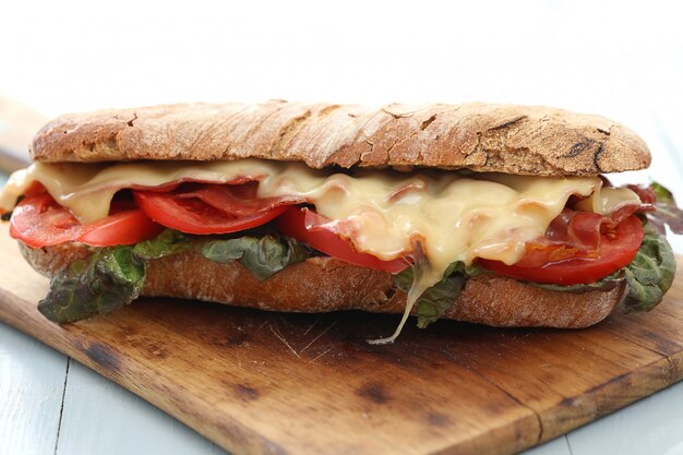 Gran sandwich vegano con verduras y queso en la mesa de tablero de madera