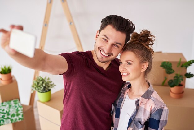 Gran selfie de pareja sonriente en su nuevo hogar.