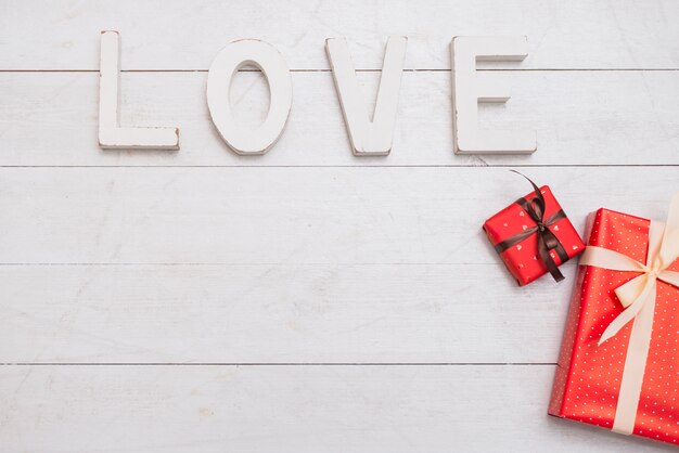 Gran título de amor blanco cerca de cajas de regalo.