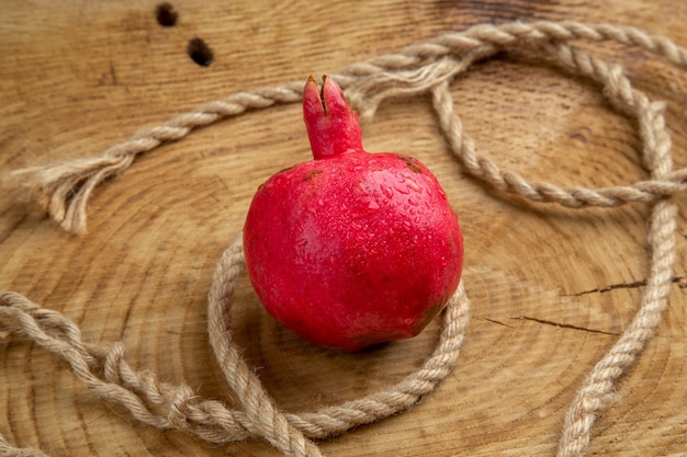 Granada roja vista frontal con cuerdas en un árbol de jugo de fruta de color de escritorio de madera