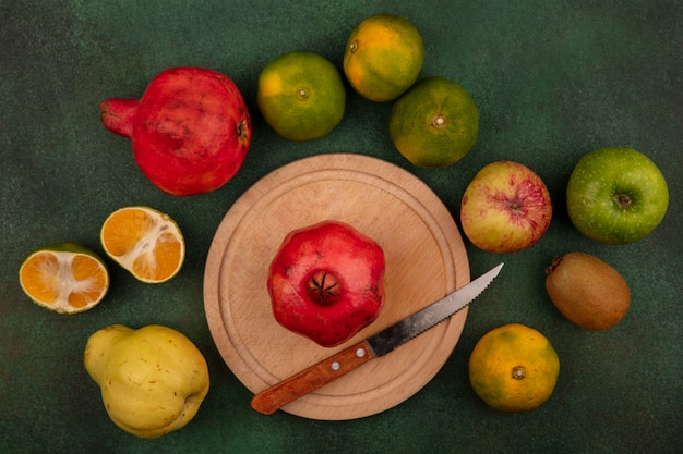 Granada de vista superior con cuchillo en soporte con pera, mandarinas y manzana