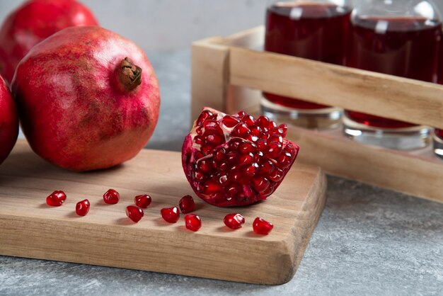 Granadas rojas frescas sobre tabla de madera con jugo.