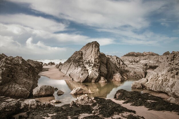 Grandes piedras y arena mojada en la playa durante el día