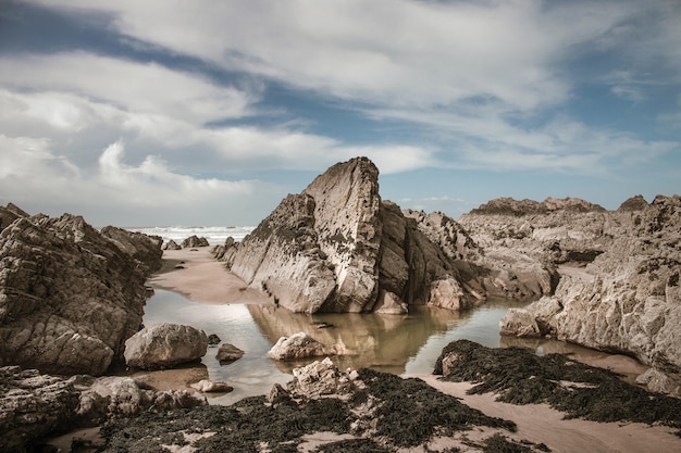 Grandes piedras y arena mojada en la playa durante el día