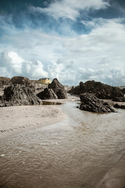 Grandes piedras y arena mojada en la playa durante el día