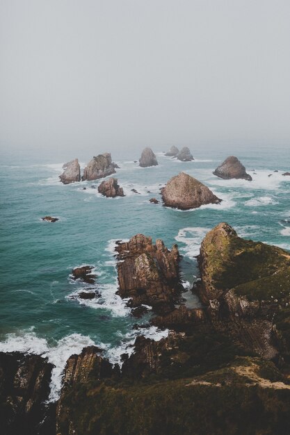 Grandes rocas en Nugget Point Ahuriri, Nueva Zelanda con un fondo de niebla