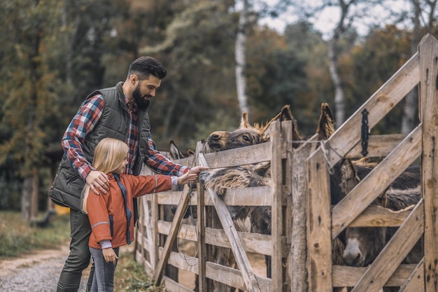 Foto gratuita en la granja farmer y una niña de pie cerca del corral de ganado.