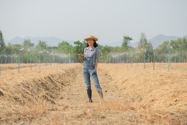 Granja inteligente. Hermoso agricultor usa tableta para controlar su granja y negocio con felicidad y sonrisa. Concepto de agricultura y negocios. El agricultor o el agrónomo examinan preparar una parcela para cultivar hortalizas.