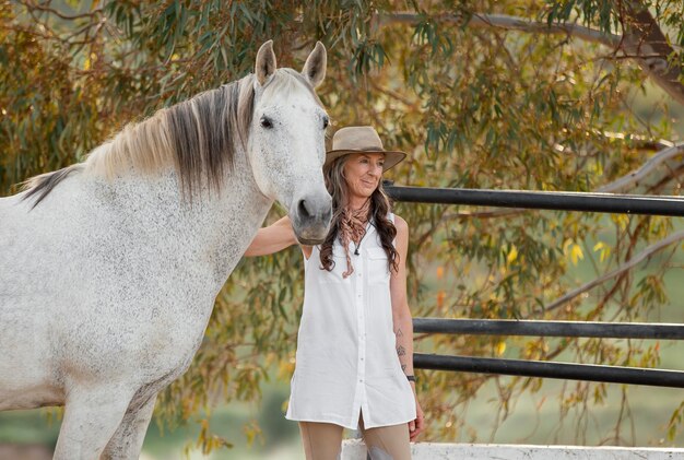 Granjera sonriente acariciando a su caballo