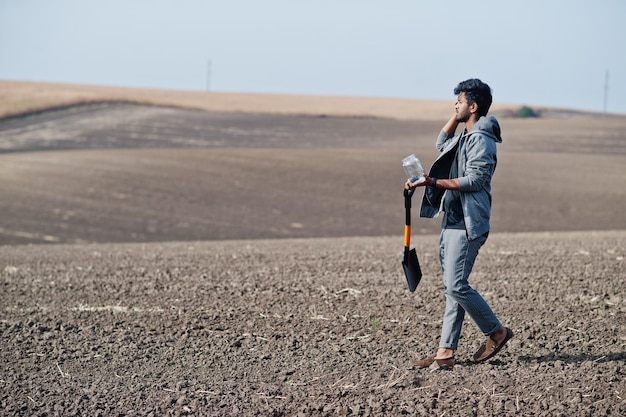 Granjero agrónomo del sur de Asia con pala inspeccionando suelo negro Concepto de producción agrícola