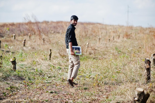 Granjero agrónomo del sur de Asia con portapapeles inspeccionando árboles cortados en el jardín agrícola Concepto de producción agrícola