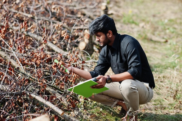 Granjero agrónomo del sur de Asia con portapapeles inspeccionando árboles cortados en el jardín agrícola Concepto de producción agrícola