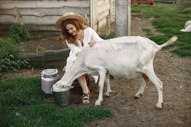 Granjero de niña con cabra blanca. Mujer y pasto verde de cabra pequeña. Granja ecológica. Concepto de granja y agricultura. Animales del pueblo.