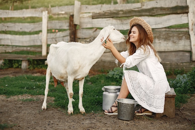 Granjero de niña con cabra blanca. Mujer y pasto verde de cabra pequeña. Granja ecológica. Concepto de granja y agricultura. Animales del pueblo.