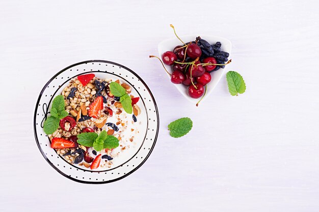 Foto gratuita granola, fresas, cerezas, bayas madreselva, nueces y yogurt en un tazón